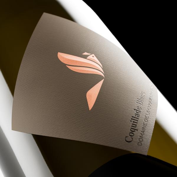 Bottle of Coquillade Blanc, a white wine from Domaine de la Coquillade, with a gold label and lark logo