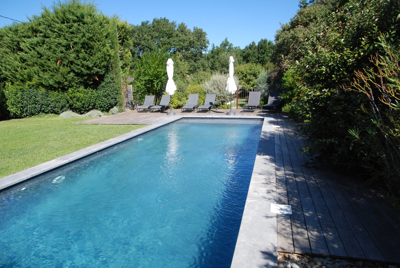 Swimming pool at La Maison Magnarelles in the Luberon Outdoor swimming pool at La Maison Magnarelles with wooden terrace and sun loungers