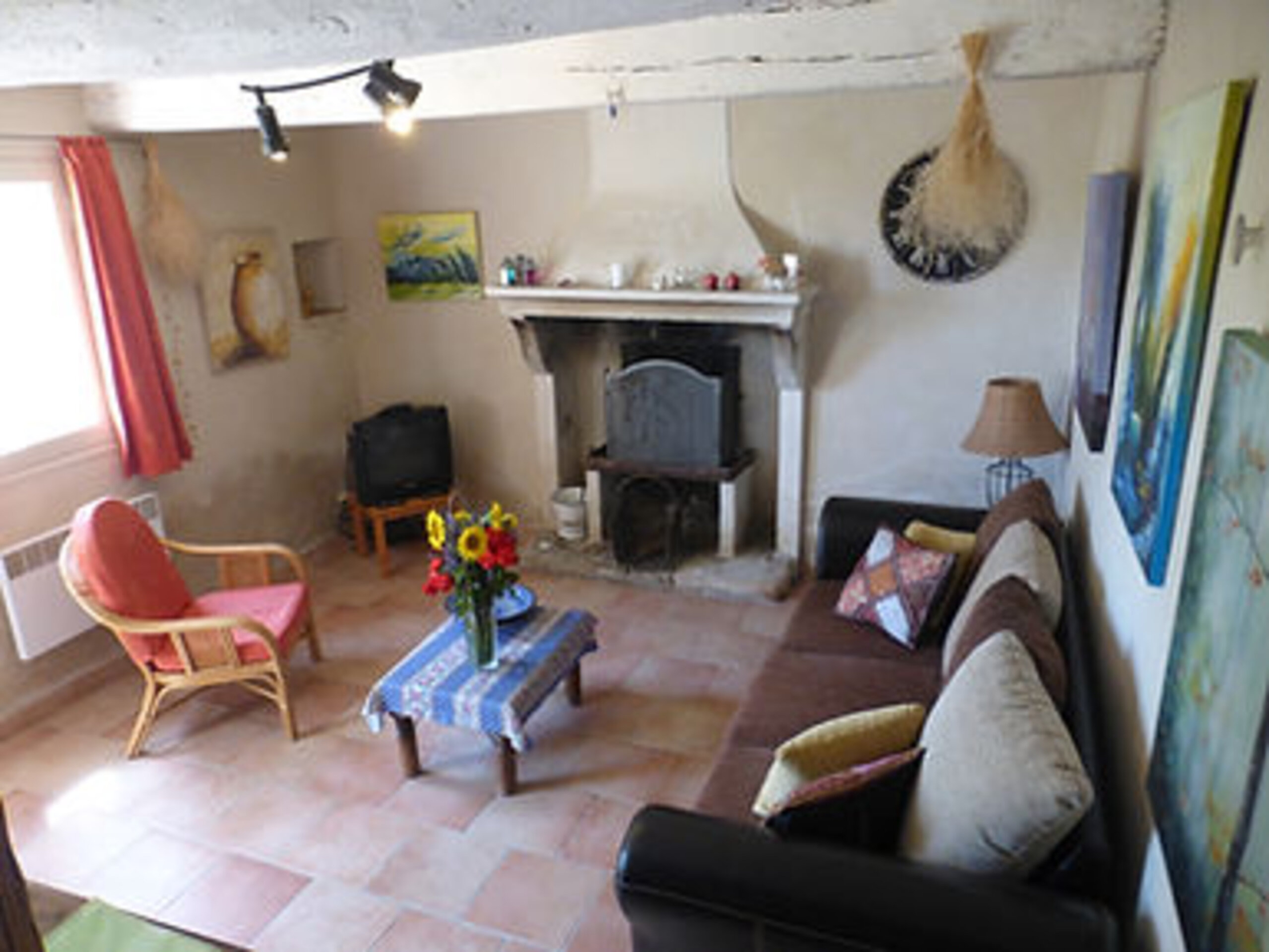 Living room of the Rosalie gîte with old fireplace, sofa and Provençal decor