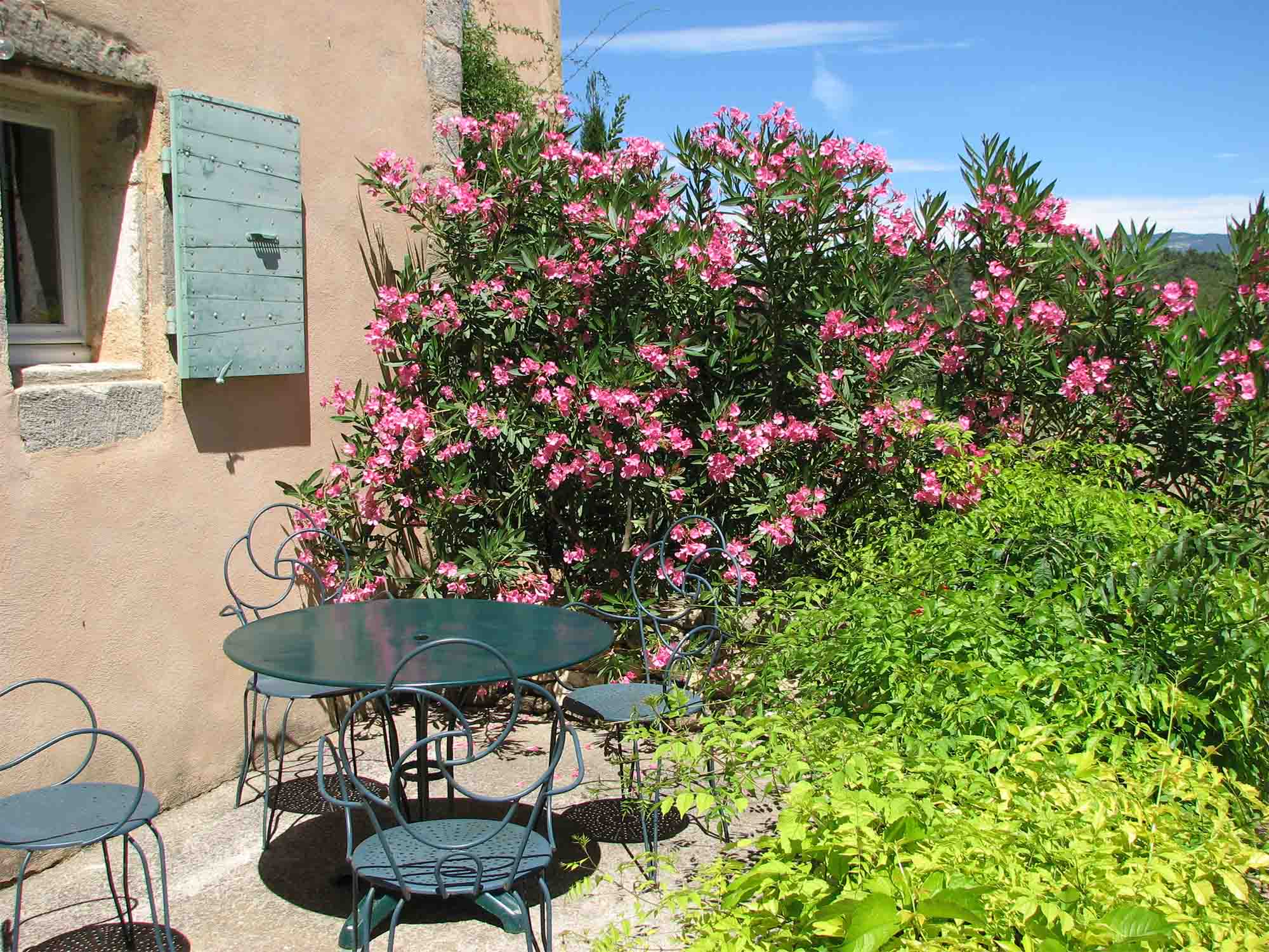 Private terrace at Maison de Rosalie with wrought iron furniture and garden flowers