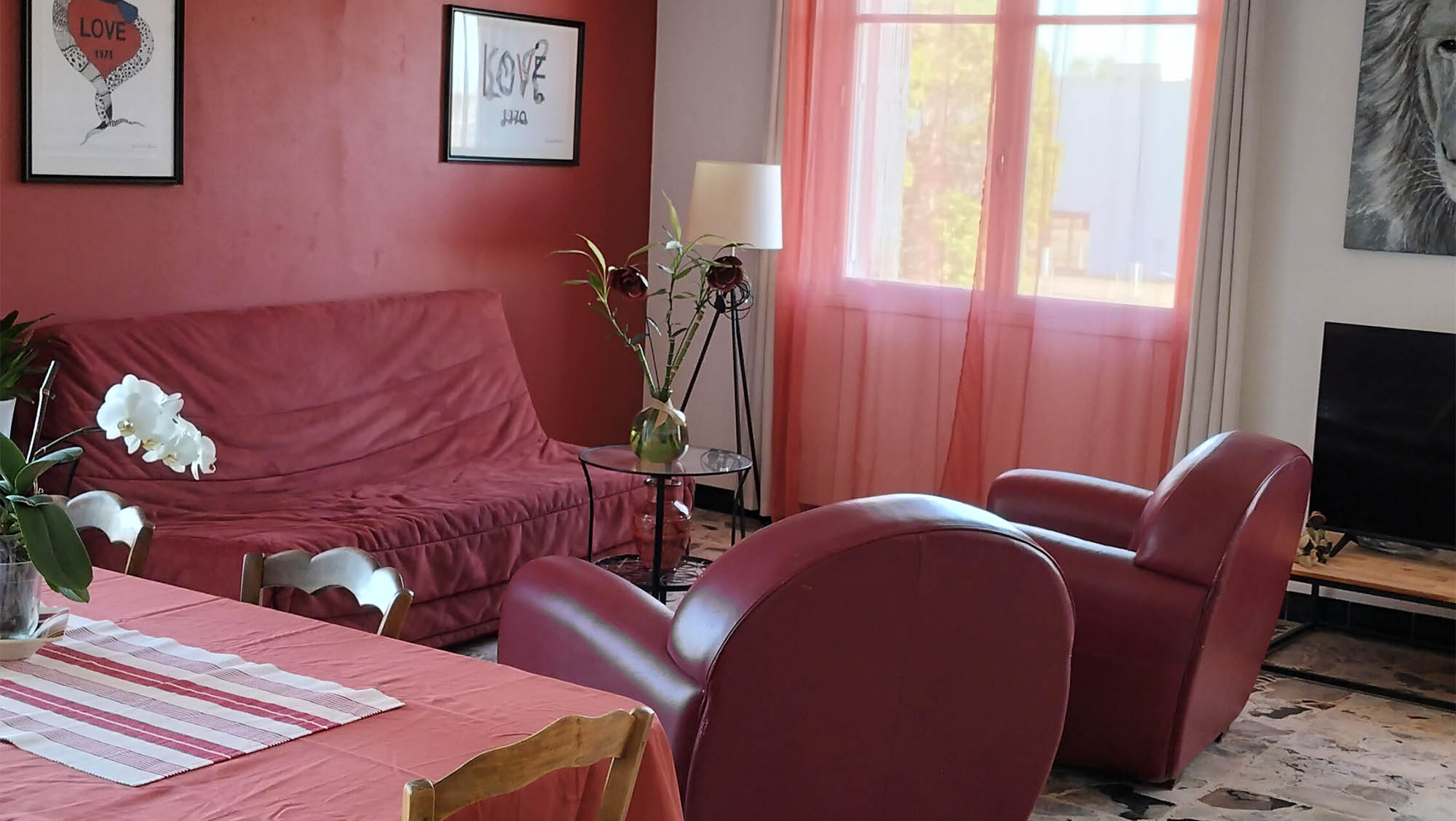 Bright and spacious living room with red armchairs at La Petite Reine