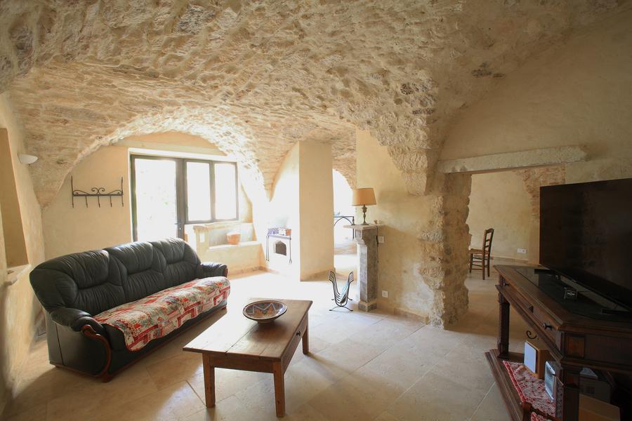 Stone-vaulted living room of La Petite Maison des Garrigues, with sofa and television