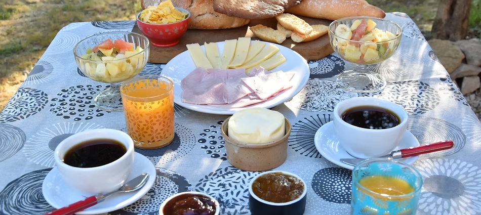 Homemade outdoor breakfast with hot drinks, fruits, cheese, and jams