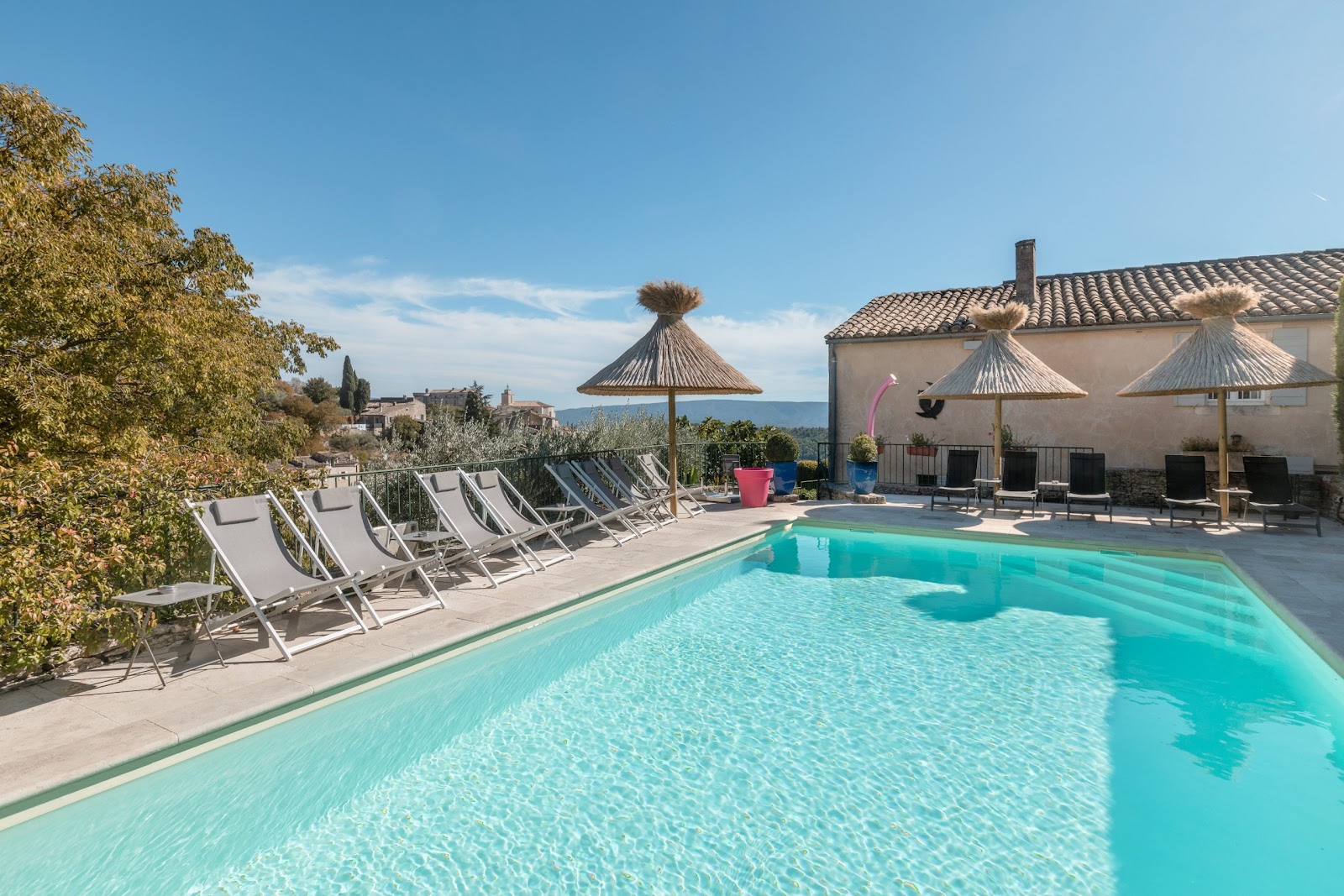 Outdoor pool at the hotel Le Mas des Romarins in Gordes with deckchairs and an unobstructed view of the Luberon