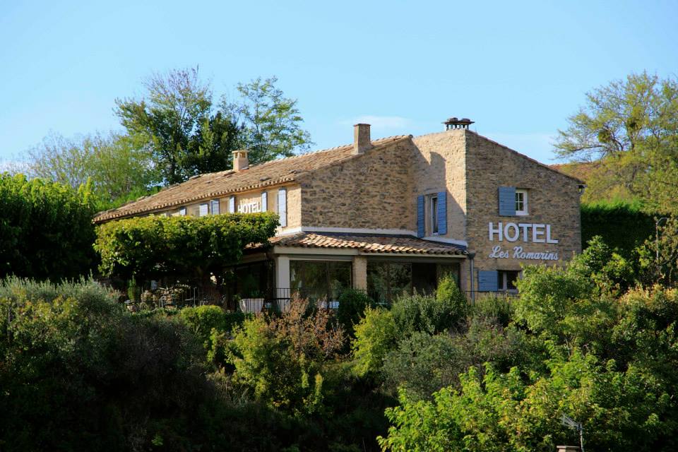 Stone facade of the Le Mas des Romarins hotel surrounded by greenery, in Gordes in the Luberon
