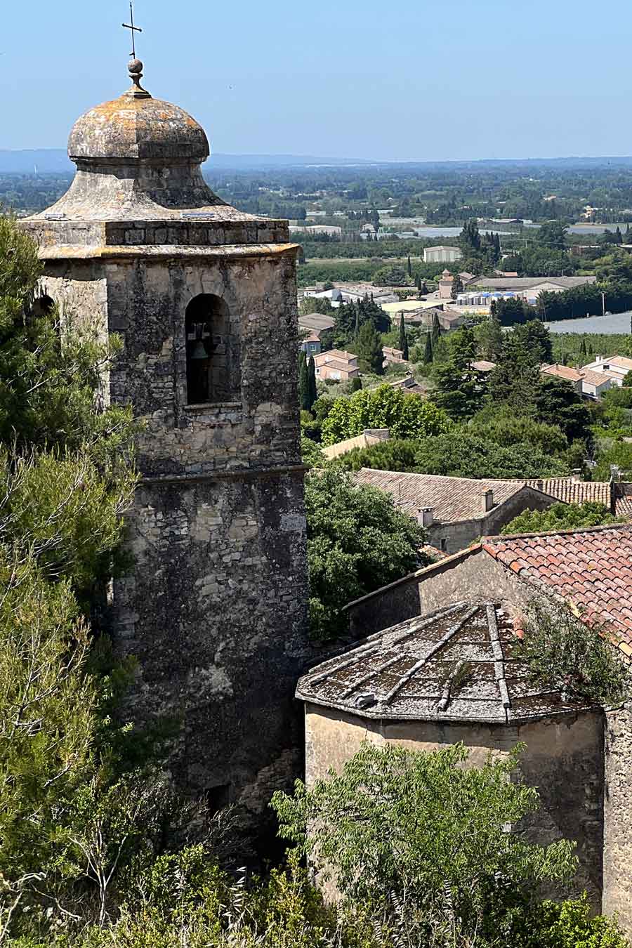 View of the bell tower and rooftops of the old village of Lagnes with the plain in the background