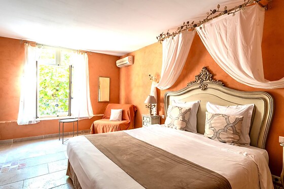 Elegant room at Mas des Grès with king-size bed, ochre tones and natural light