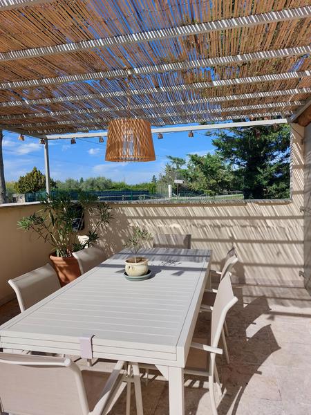 Shaded terrace with outdoor dining table and countryside views at Mas d’Anaé in the Luberon