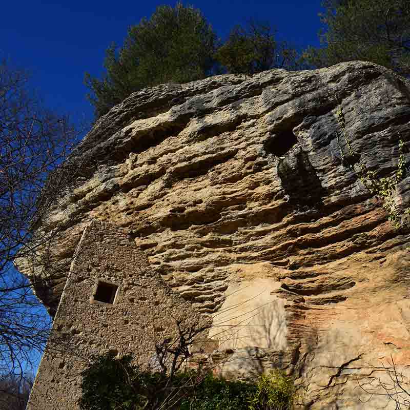 Troglodyte dwellings carved into the rock at Les Beaumettes, a testament to human adaptation to the Luberon landscape