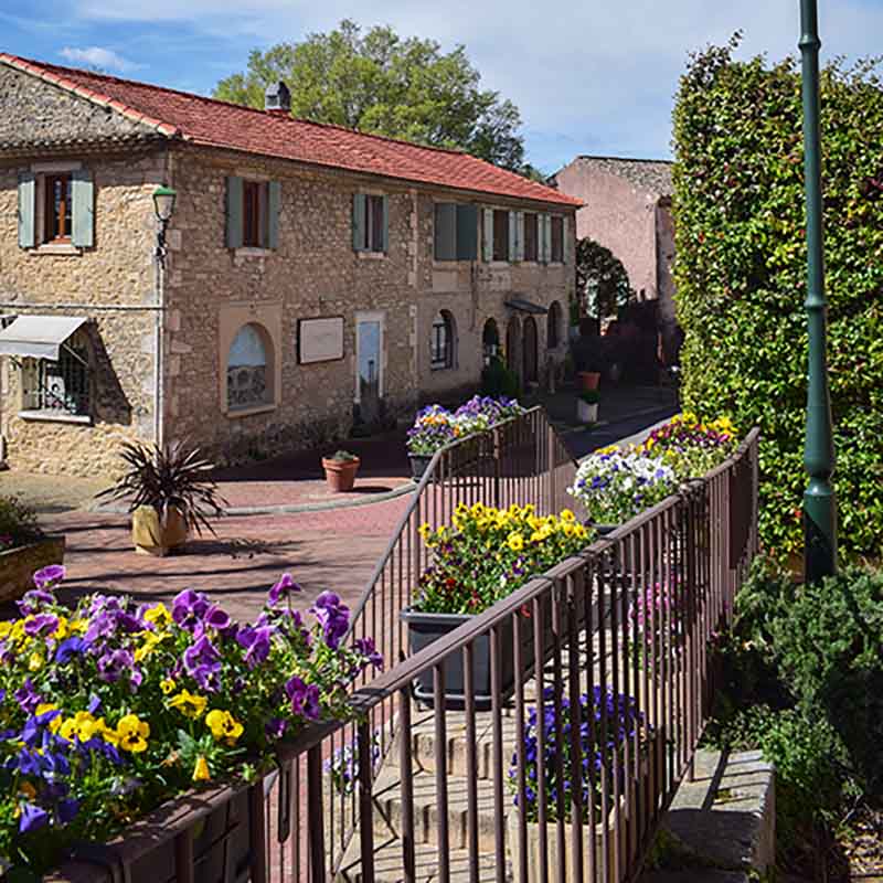 Stone houses and a flower-lined path in the heart of the village of Les Beaumettes, in the Luberon