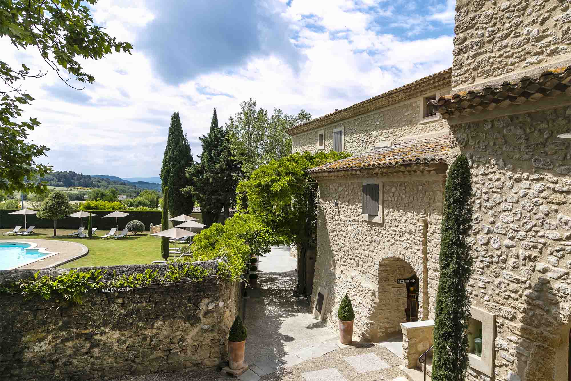 View of Le Mas de Guilles with stone buildings and swimming pool in the Luberon