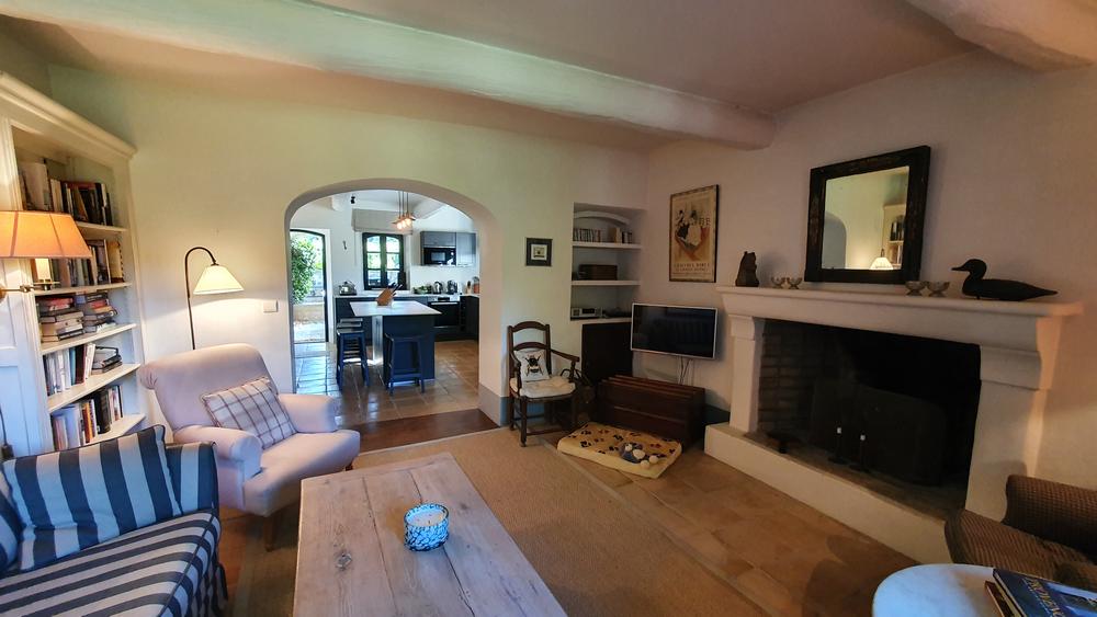 Warm living room of Mas Petit Collongue with sofa, fireplace and access to the kitchen