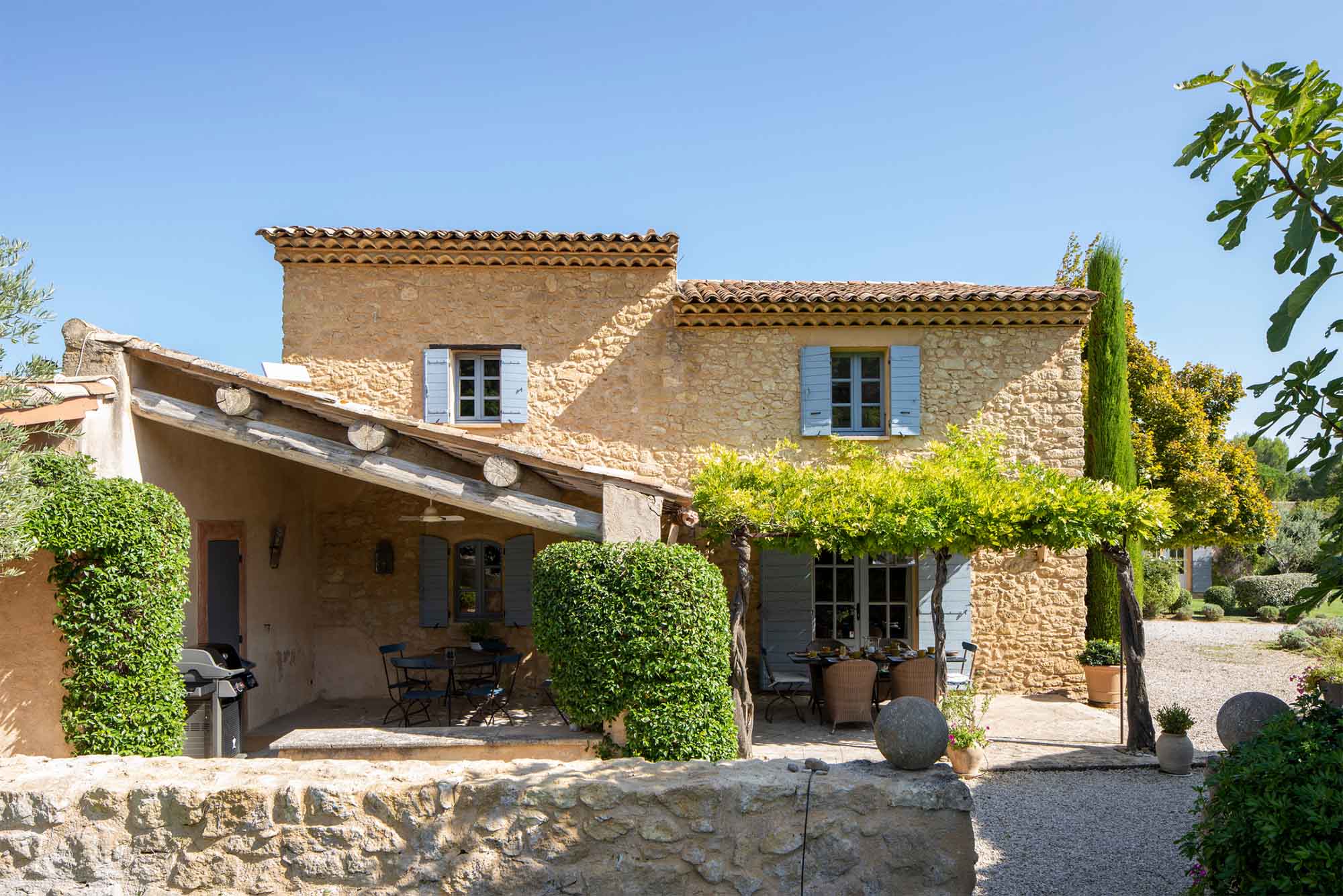 Stone façade of Mas Petit Collongue in Lourmarin with shaded terrace and garden