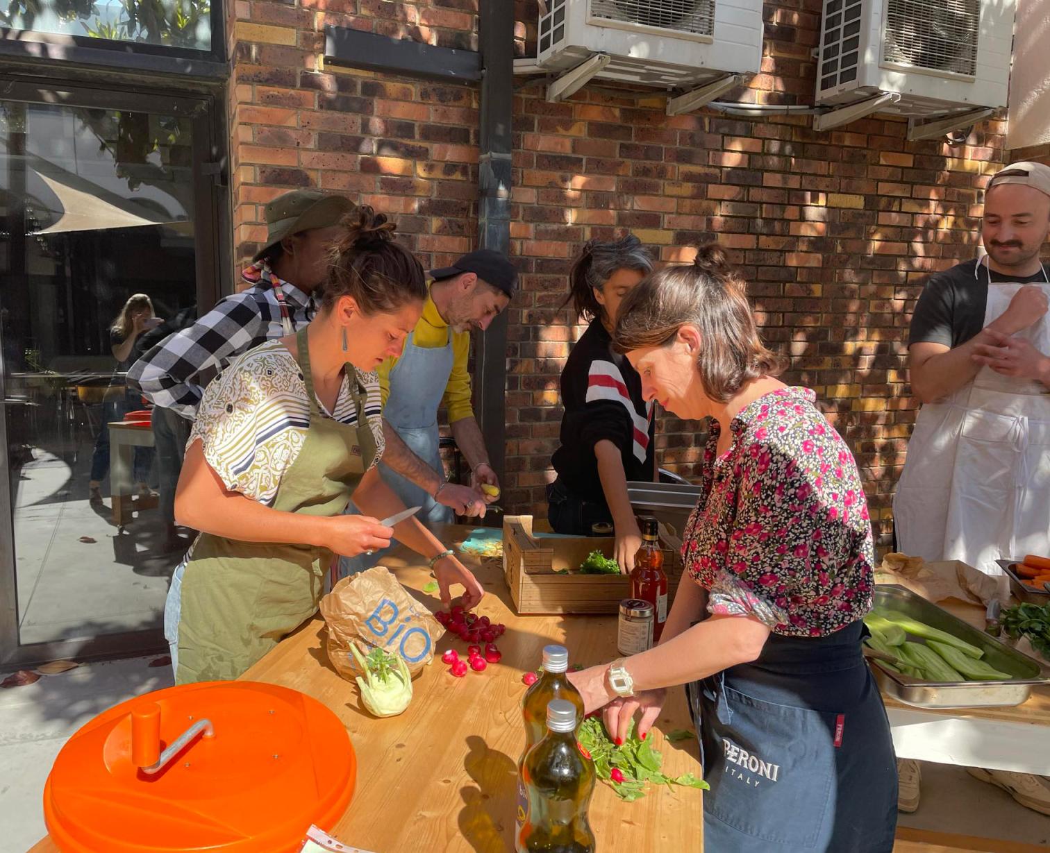 Participants preparing vegetables and cooking together during a collaborative cooking workshop at Festival Confit!