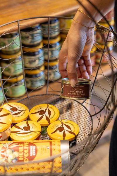 Hand picking up a gourmet product from a basket at Les Délices du Luberon