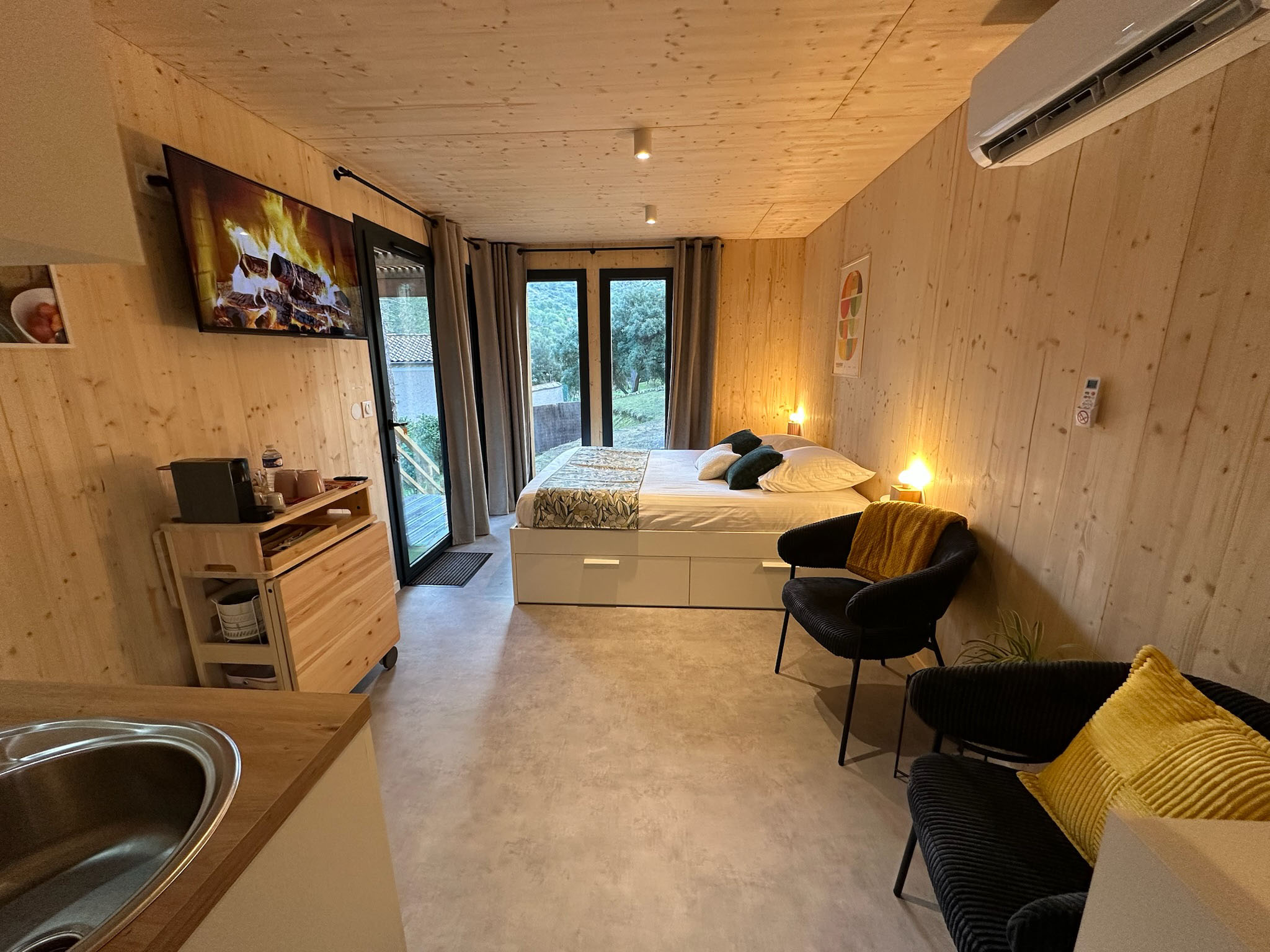 Interior of the cabin with a double bed, armchairs, television and kitchenette