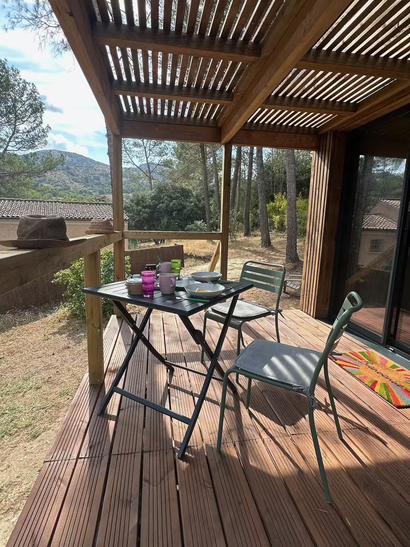 Covered terrace of the cabin with a table and chairs overlooking the trees