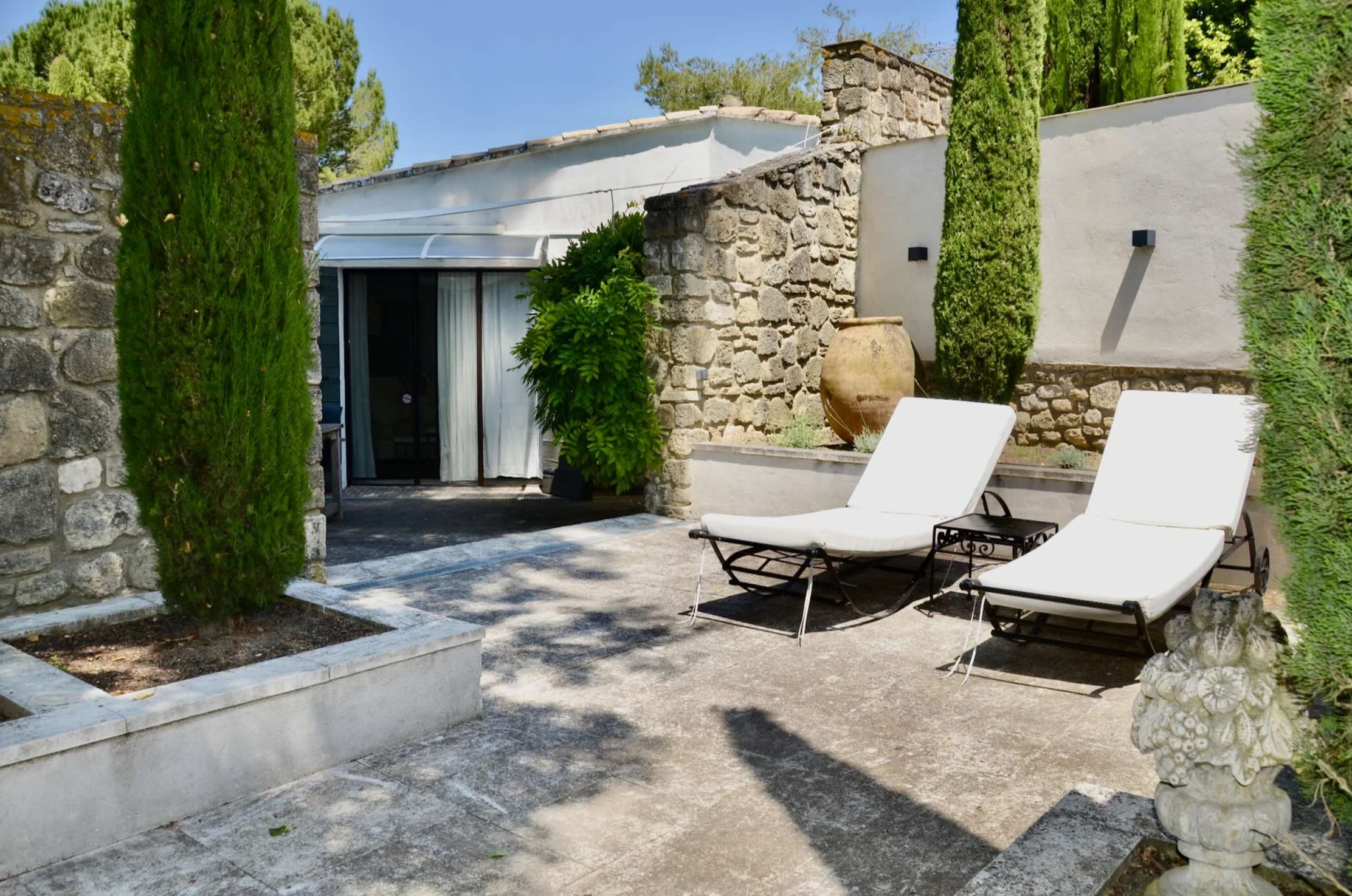 Outdoor relaxation area with sun loungers, Les Oliviers house in Oppède Outdoor relaxation area with sun loungers and cypress trees in the garden of Les Oliviers house in Oppède, Luberon