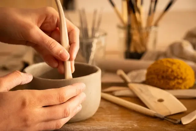 Clay hand-building during a pottery class at Atelier Chamotte in Cadenet Hands shaping a clay piece during a pottery workshop in Cadenet