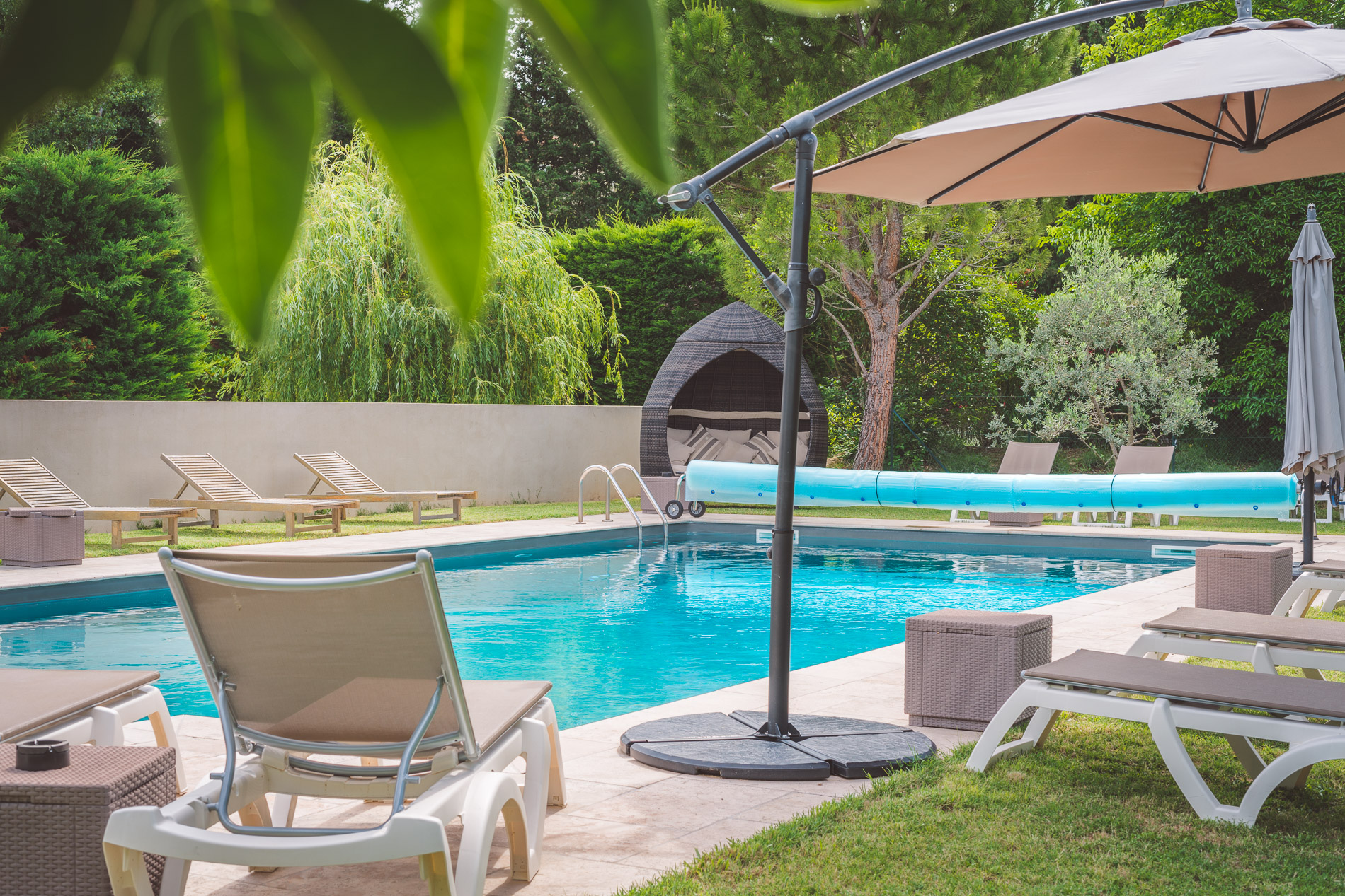 Outdoor pool and shaded park at Hôtel Le Mas du Colombier in Cadenet