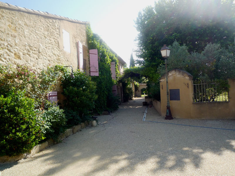 Entrance of Mas des 2 Fontaines in Cavaillon with stone facade and Mediterranean vegetation