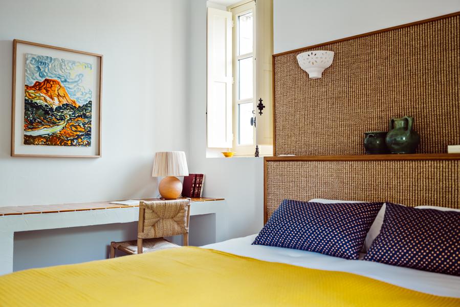 Bedroom detail at Le Moulin in Lourmarin with natural fibre headboard and comfortable bedding