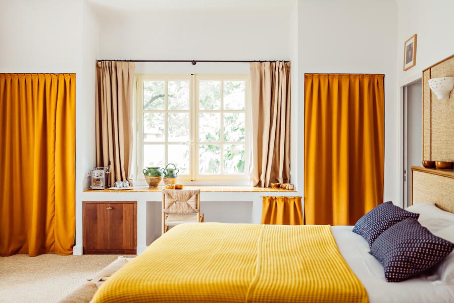 Bedroom at Le Moulin, 4-star hotel in Lourmarin, with double bed, yellow linen and ochre curtains