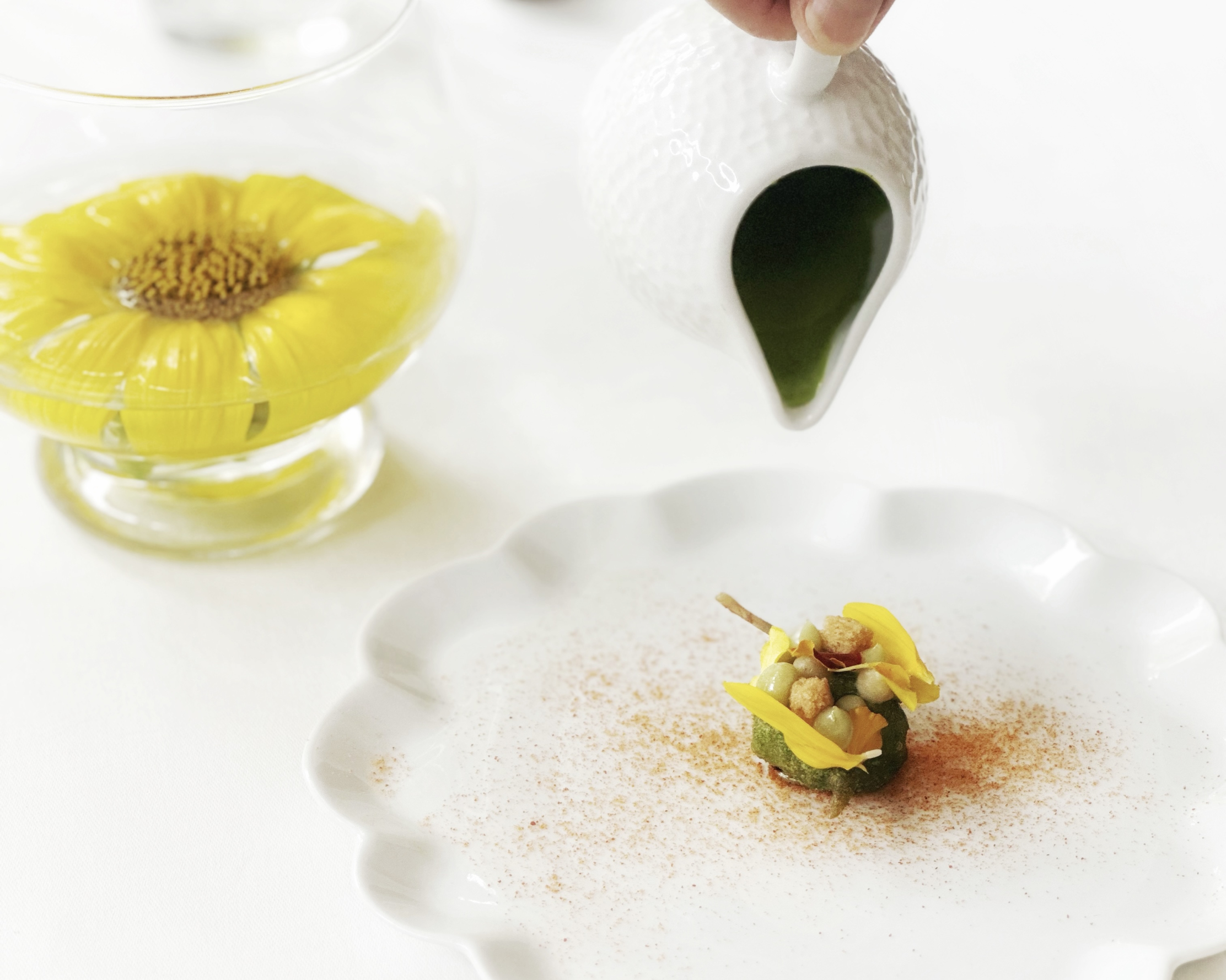 Refined gastronomic dish served at L'Olivier restaurant in the Luberon, decorated with edible yellow flowers and accompanied by a green sauce.
