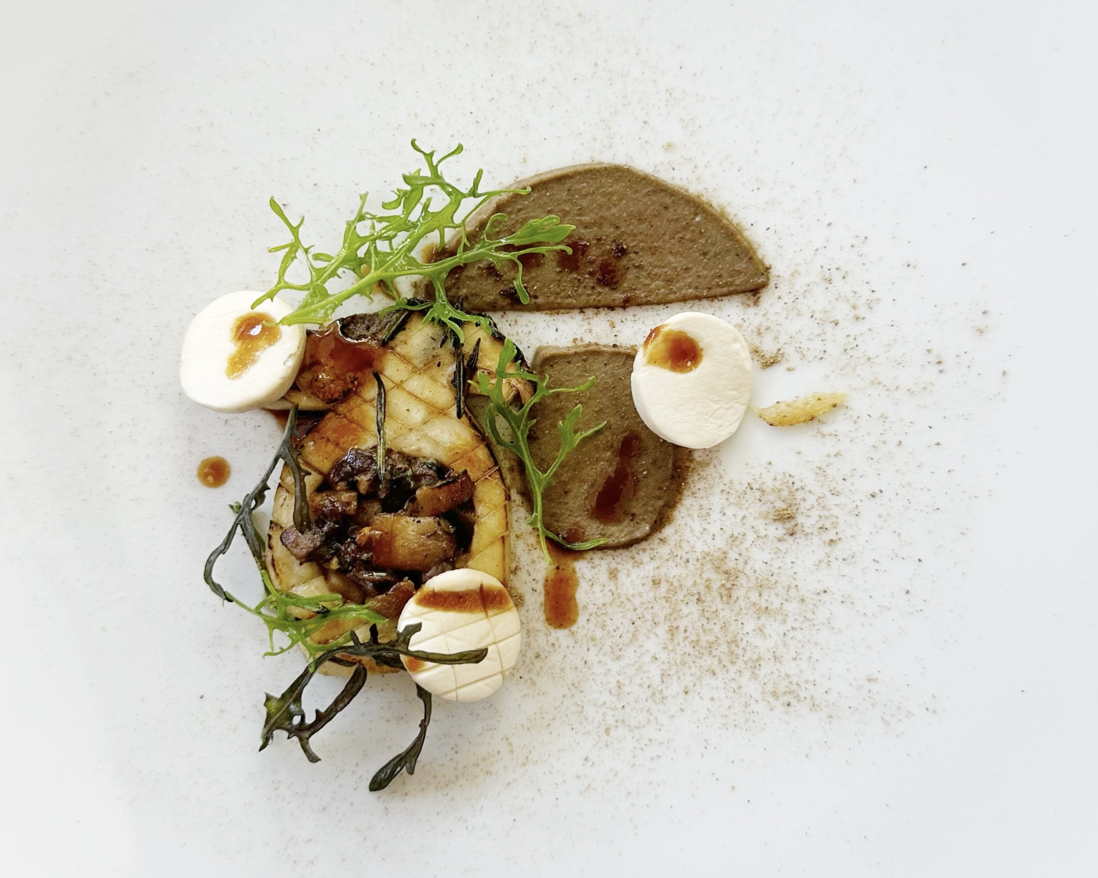 Elaborate culinary creation from L'Olivier restaurant, combining mushrooms, puree, and fresh herbs in an artistic presentation.