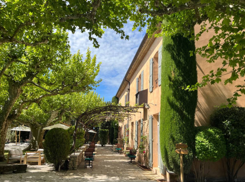 Facade of Le Mas des Grès in Lagnes and shaded terrace under centuries-old plane trees