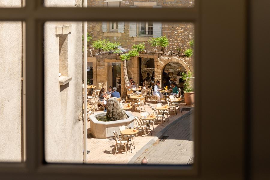 Outdoor terrace of Bacheto restaurant in Lourmarin with tables arranged around a fountain